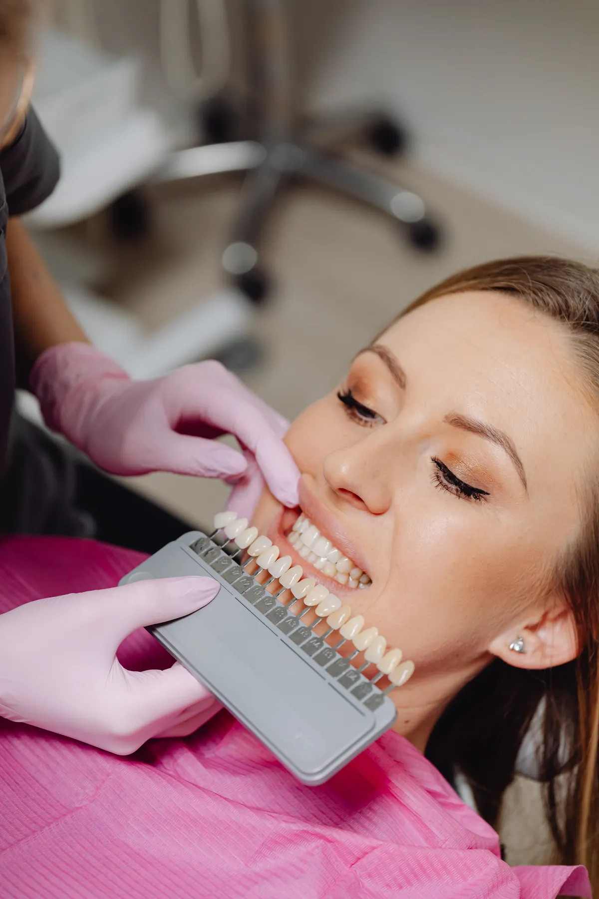 Odontóloga comparando el color de los dientes de una paciente con una guía de tonos